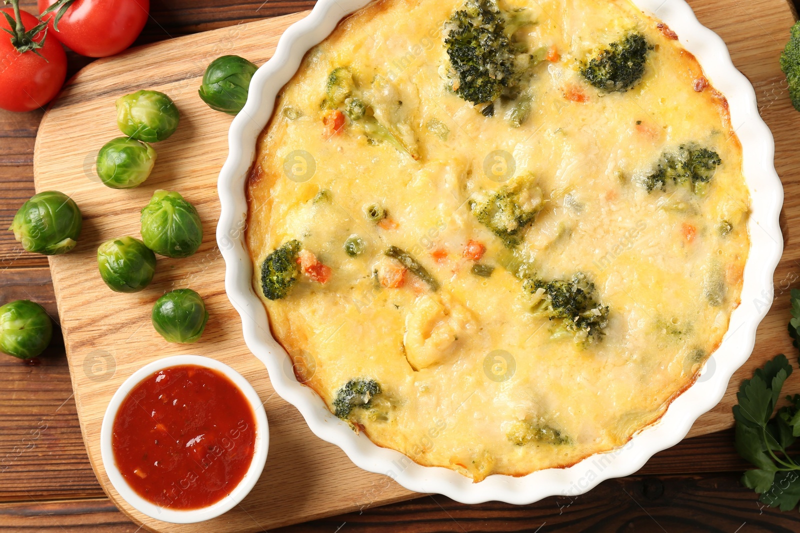 Photo of Delicious vegetable casserole, sauce and ingredients on wooden table, flat lay