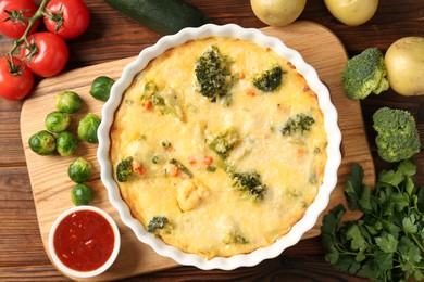 Photo of Delicious vegetable casserole, sauce and ingredients on wooden table, flat lay