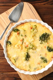 Photo of Delicious vegetable casserole and server on wooden table, top view