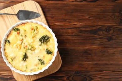 Photo of Delicious vegetable casserole and server on wooden table, top view. Space for text