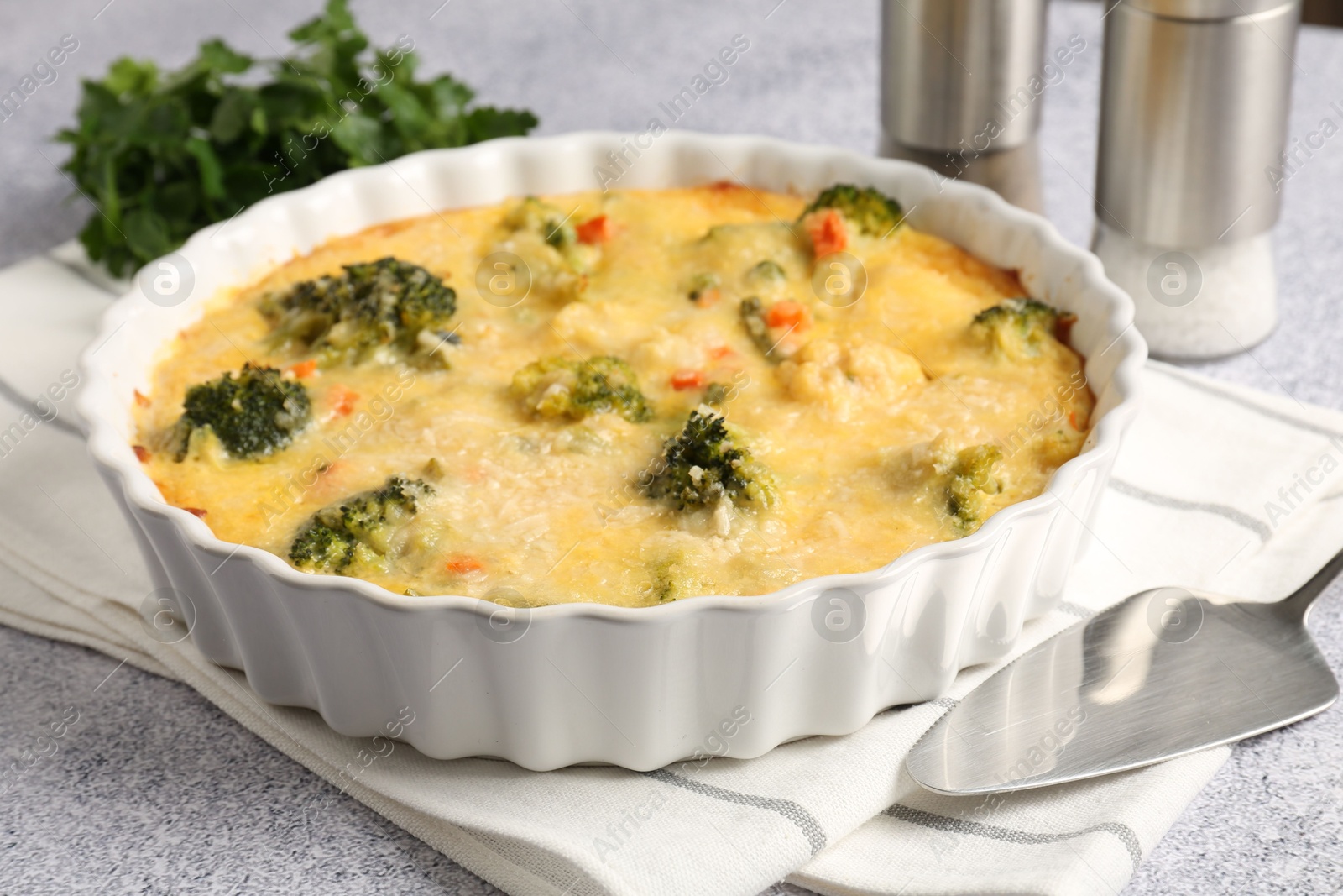 Photo of Delicious vegetable casserole and server on light table, closeup