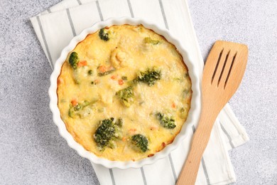 Photo of Delicious vegetable casserole and turner on light table, top view