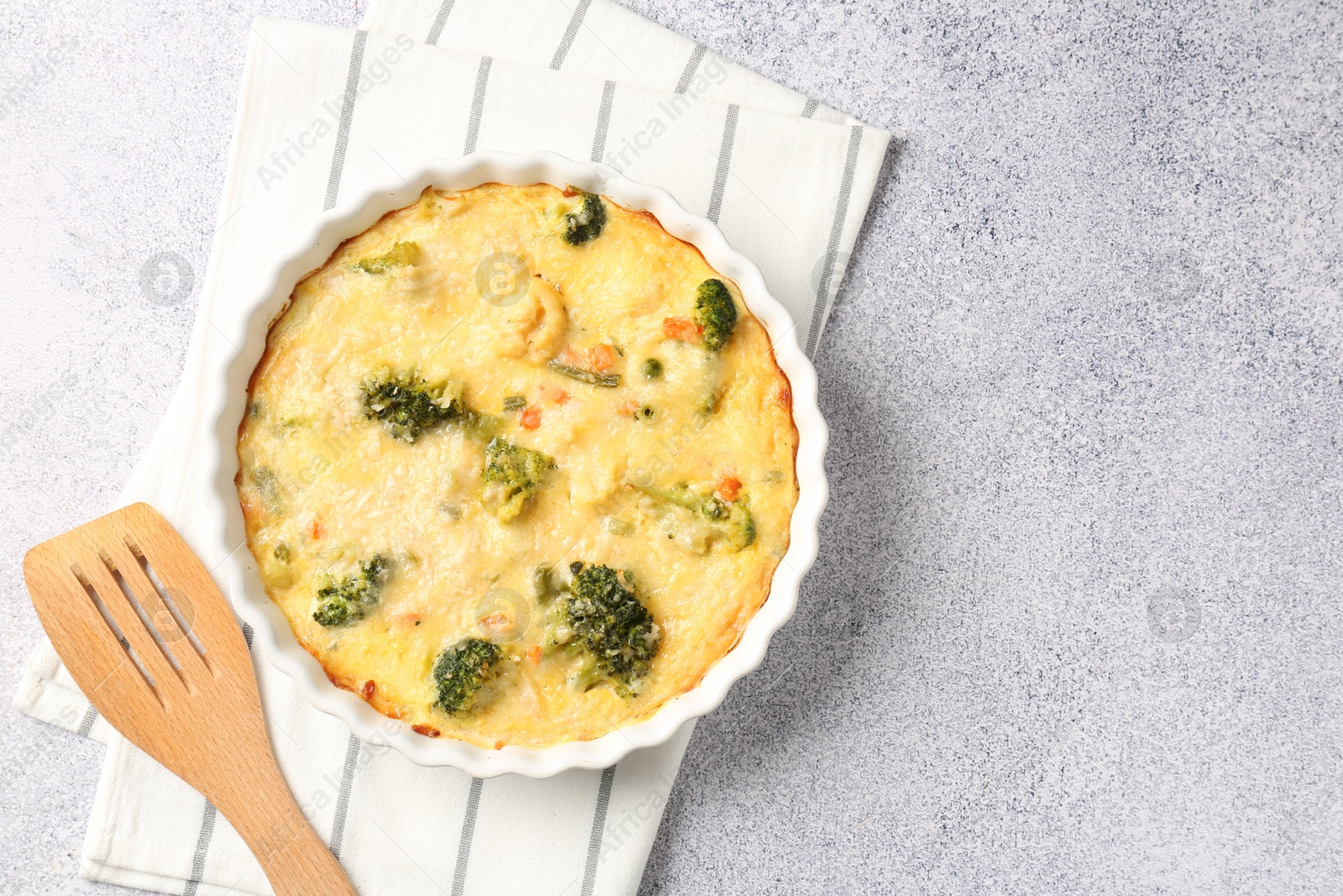 Photo of Delicious vegetable casserole and turner on light table, top view. Space for text