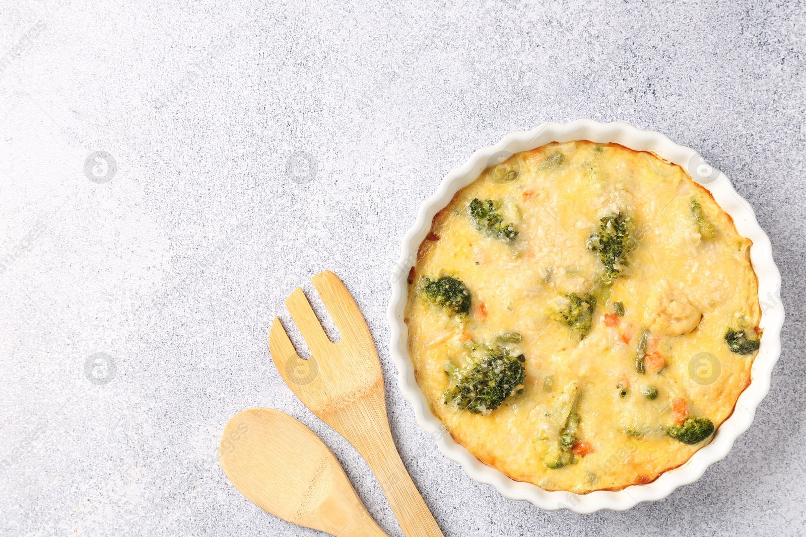 Photo of Delicious vegetable casserole and utensils on light table, top view. Space for text