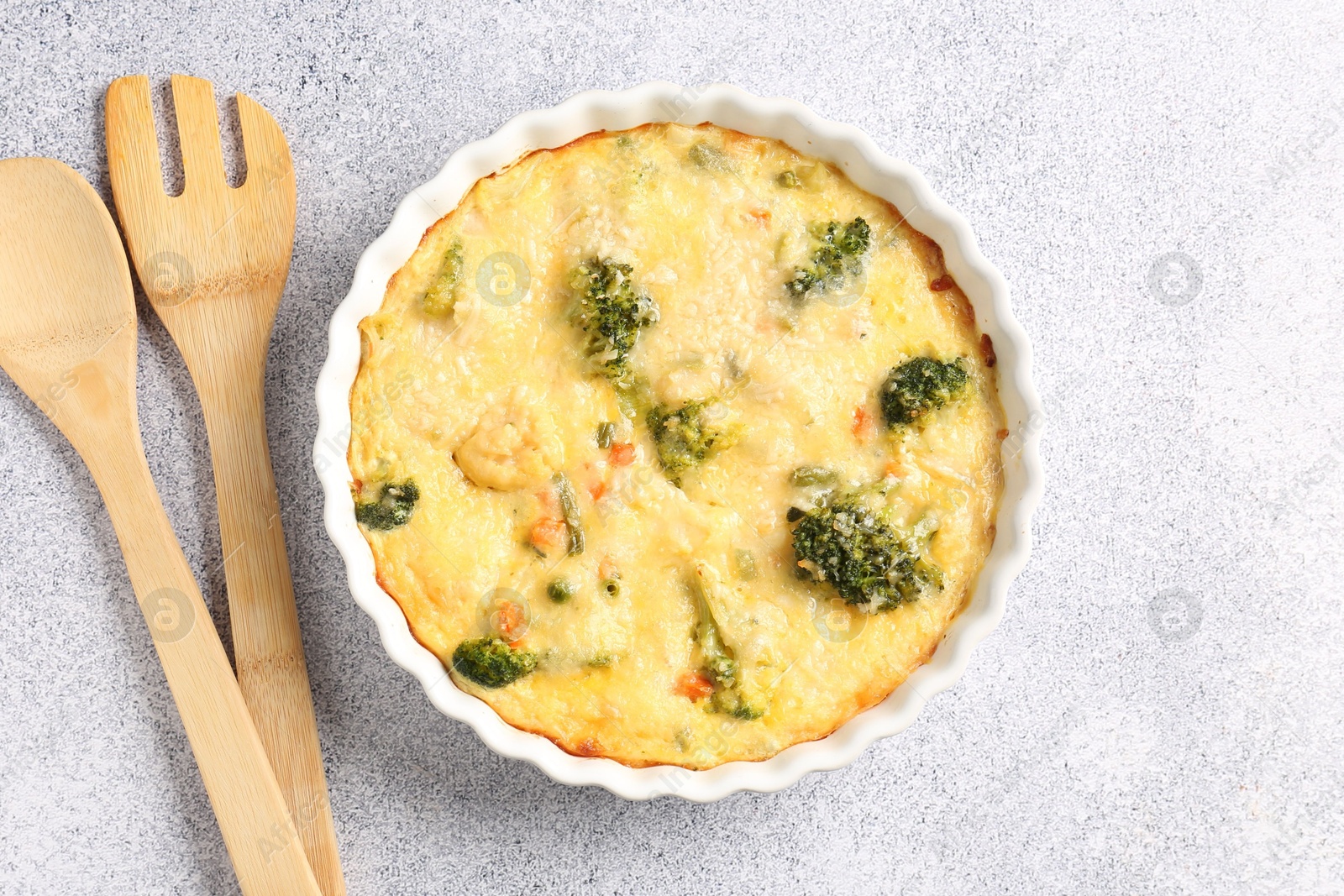 Photo of Delicious vegetable casserole and utensils on light table, top view