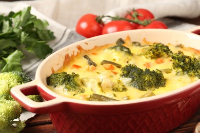 Photo of Delicious vegetable casserole and ingredients on wooden table, closeup