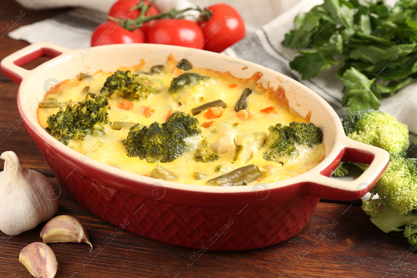 Photo of Delicious vegetable casserole and ingredients on wooden table, closeup