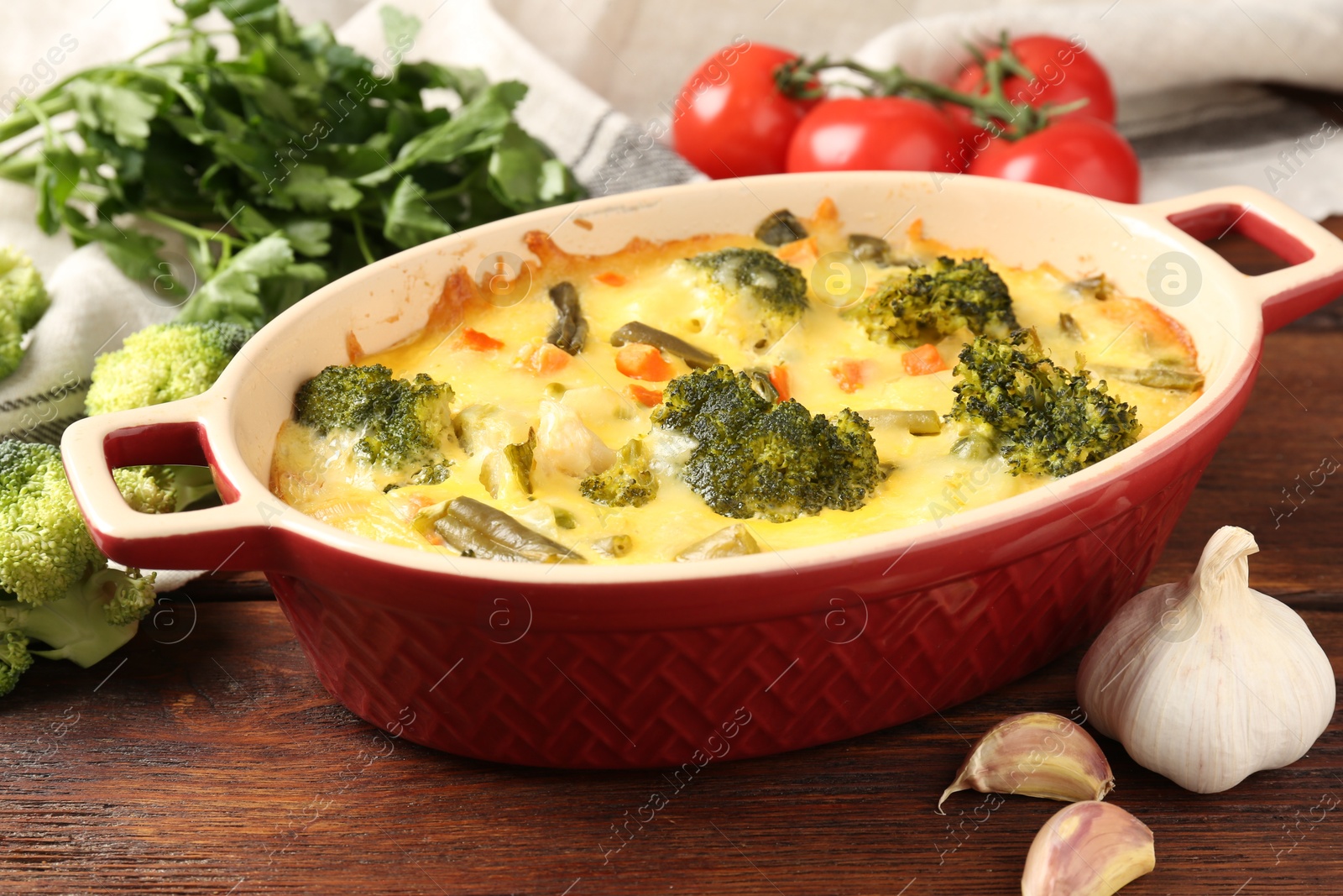 Photo of Delicious vegetable casserole and ingredients on wooden table, closeup