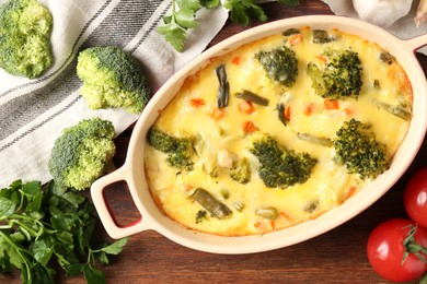 Photo of Delicious vegetable casserole and ingredients on wooden table, flat lay