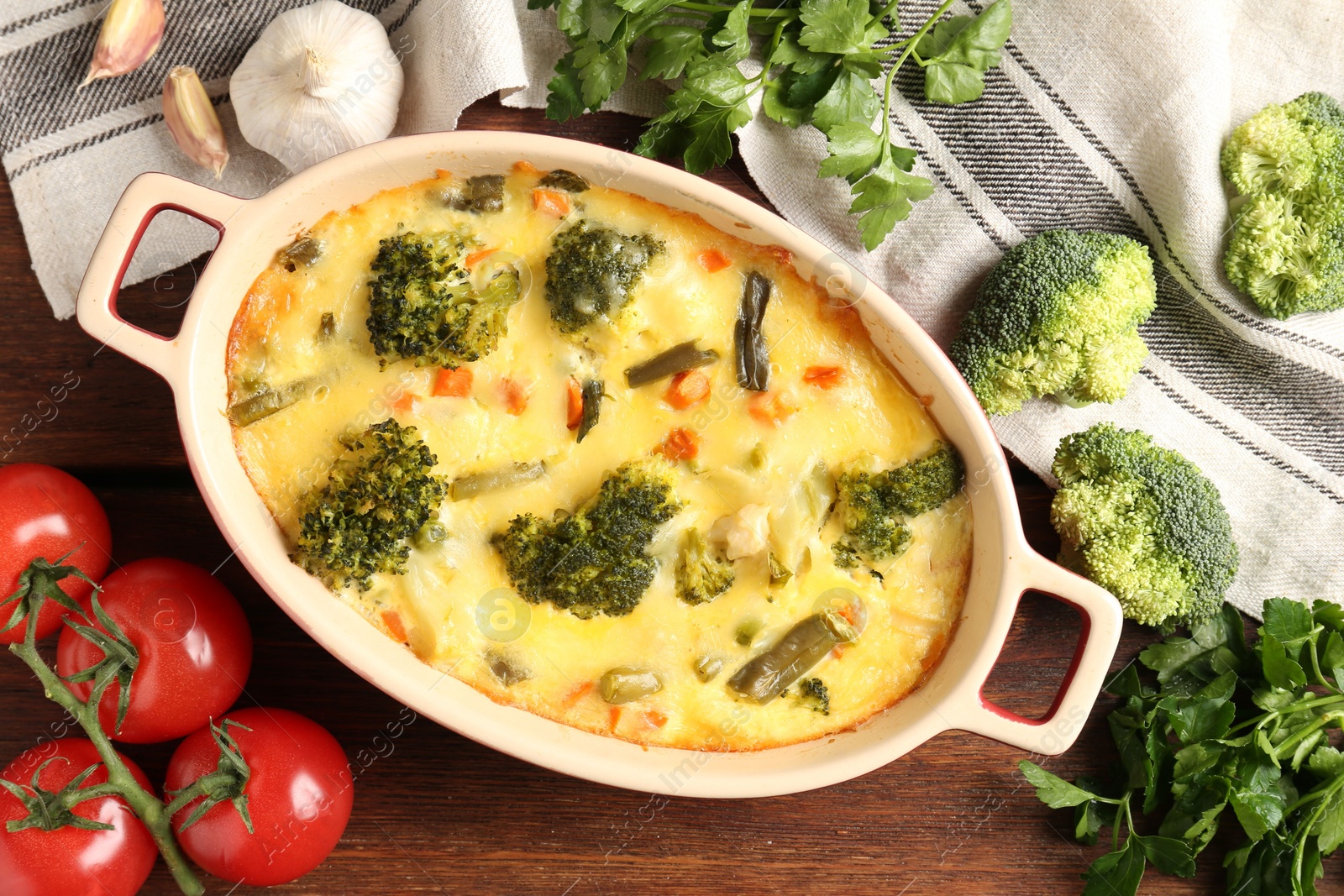 Photo of Delicious vegetable casserole and ingredients on wooden table, flat lay