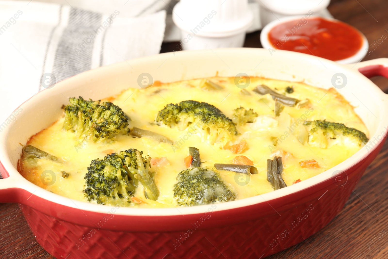 Photo of Delicious vegetable casserole and sauce on wooden table, closeup