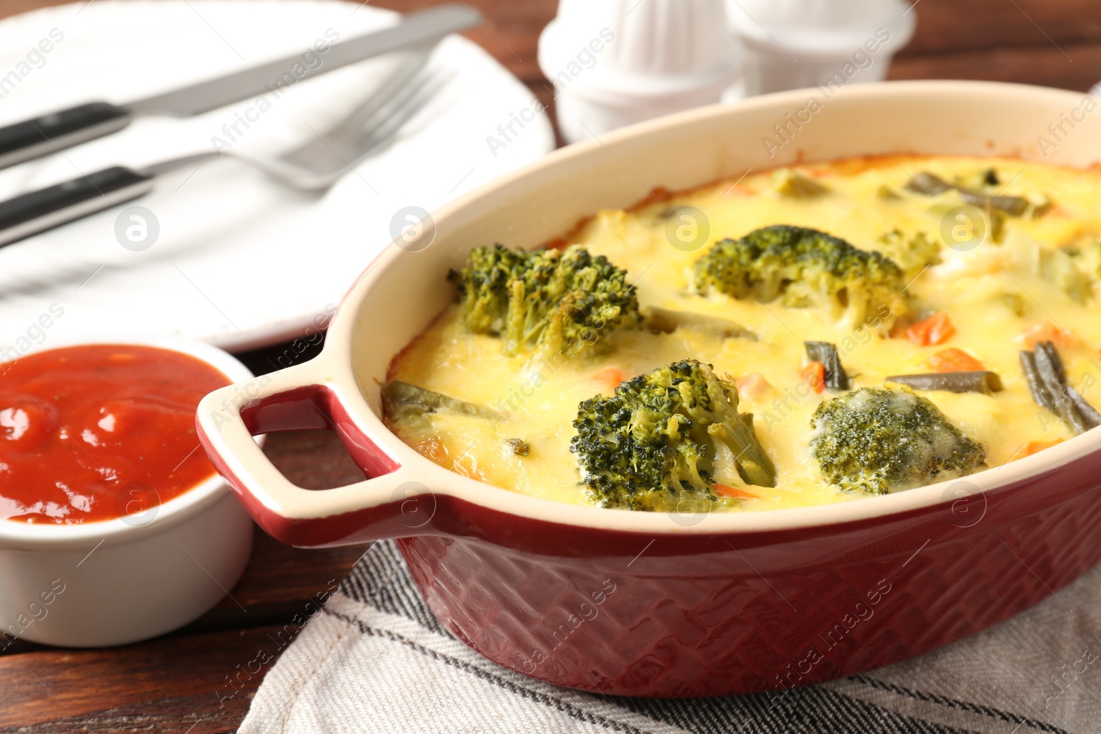 Photo of Delicious vegetable casserole and sauce on wooden table, closeup