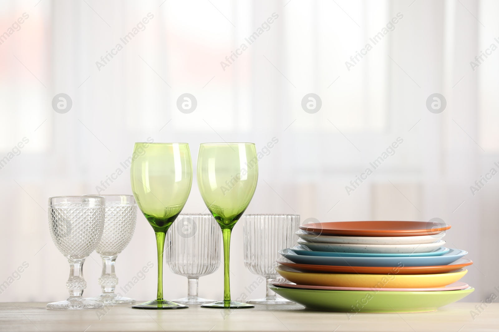 Photo of Empty clean glasses and plates on table indoors