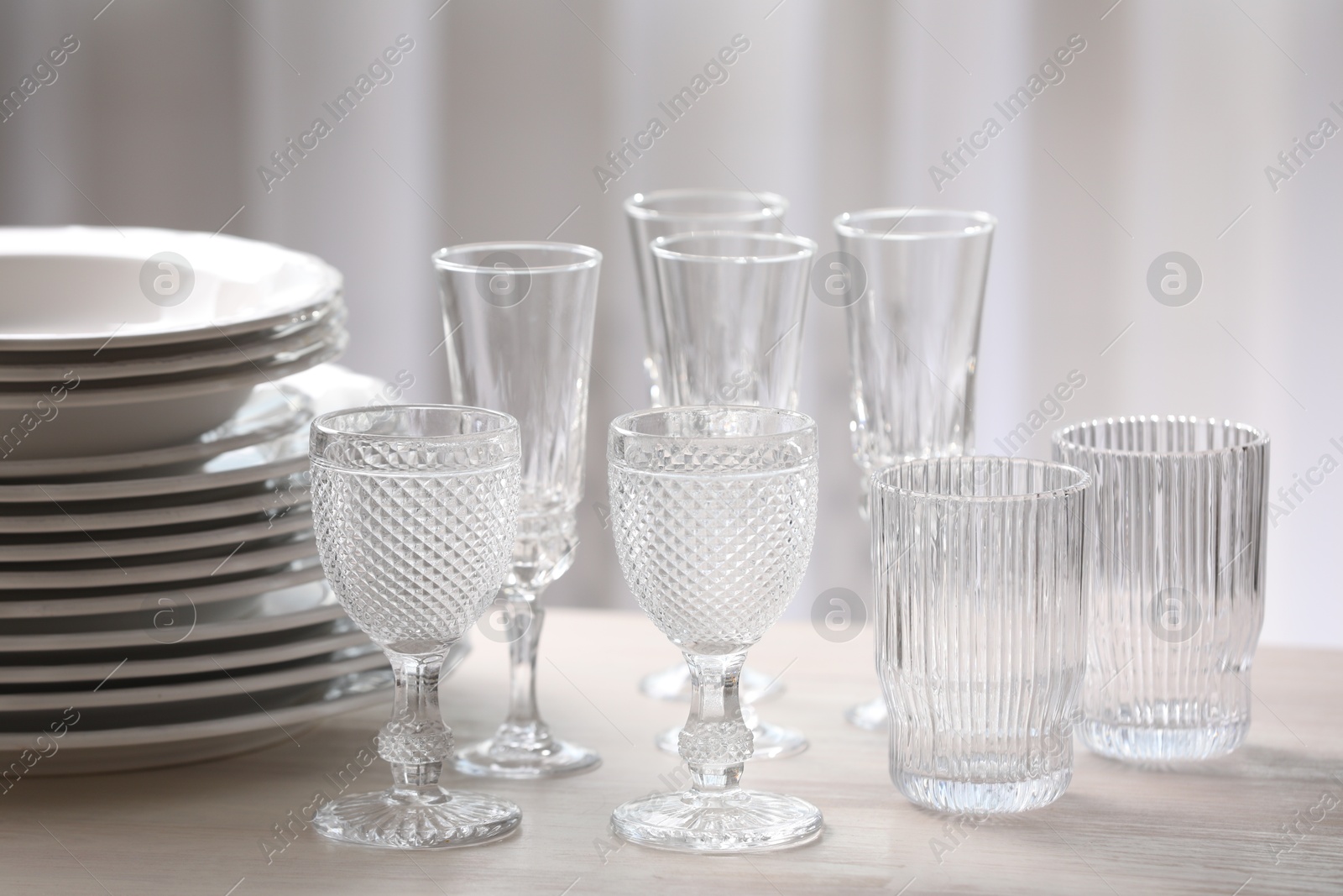 Photo of Empty clean glasses and plates on wooden table indoors