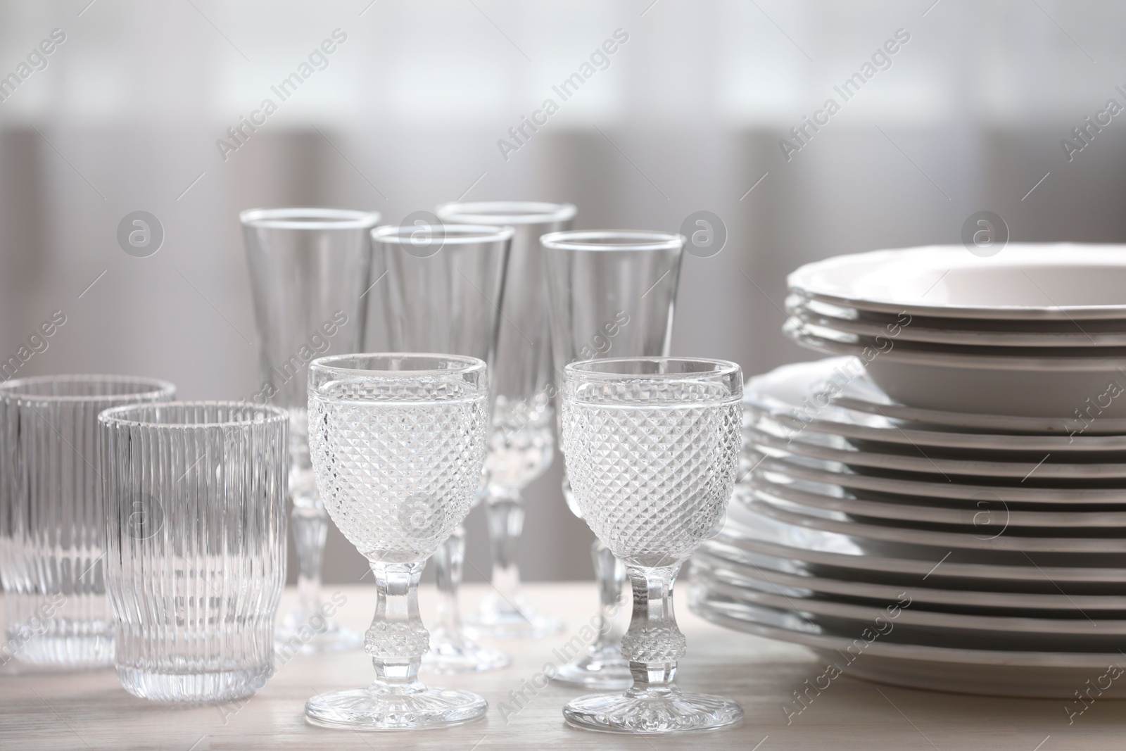 Photo of Empty clean glasses and plates on wooden table indoors