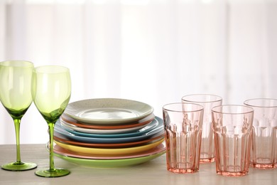 Photo of Empty clean glasses and plates on wooden table indoors