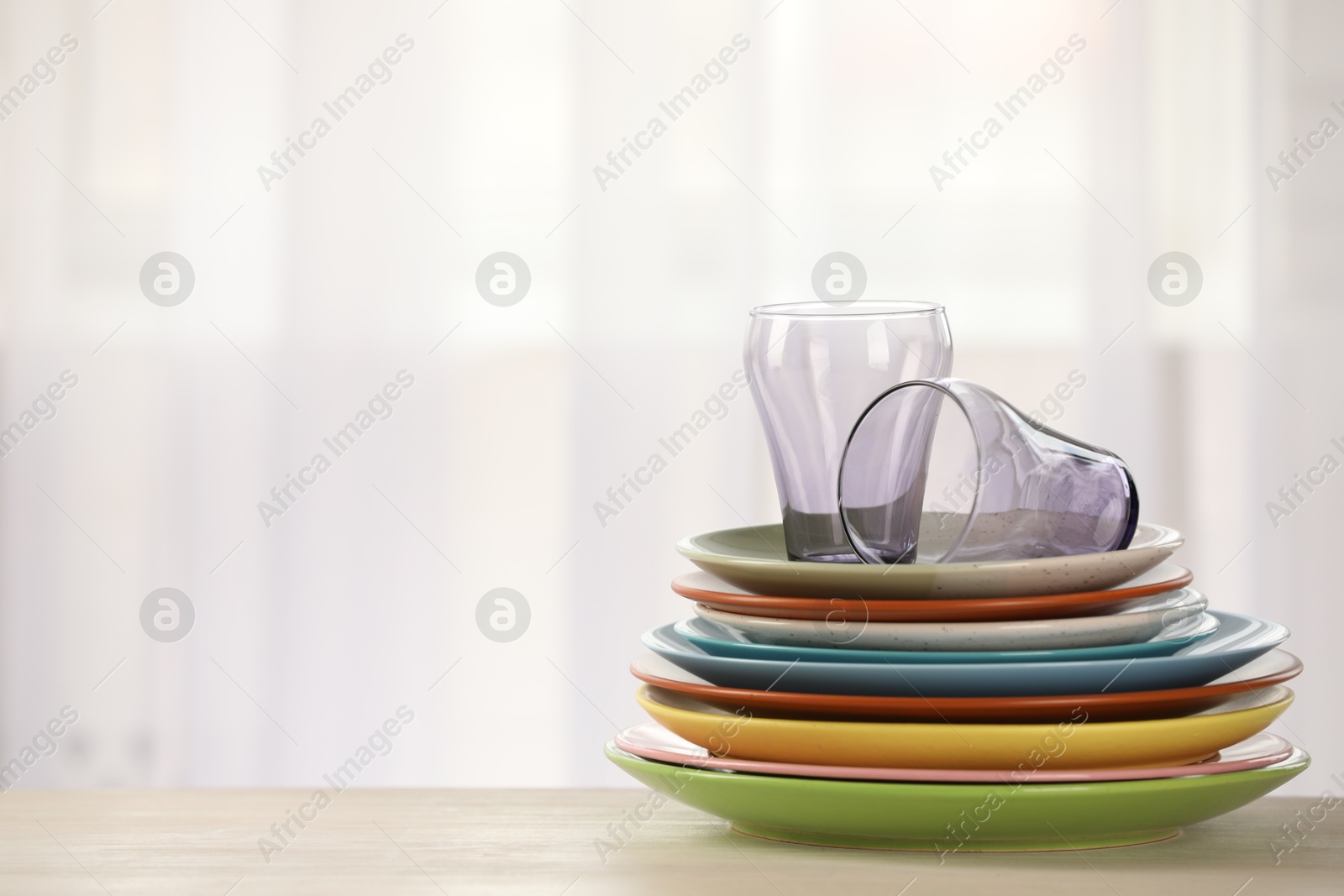 Photo of Empty clean glasses and plates on wooden table indoors, space for text