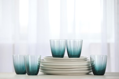 Photo of Empty clean glasses and plates on table indoors