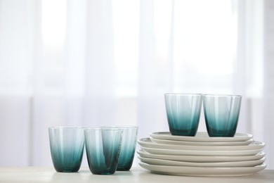 Photo of Empty clean glasses and plates on table indoors