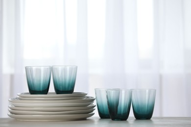 Photo of Empty clean glasses and plates on table indoors