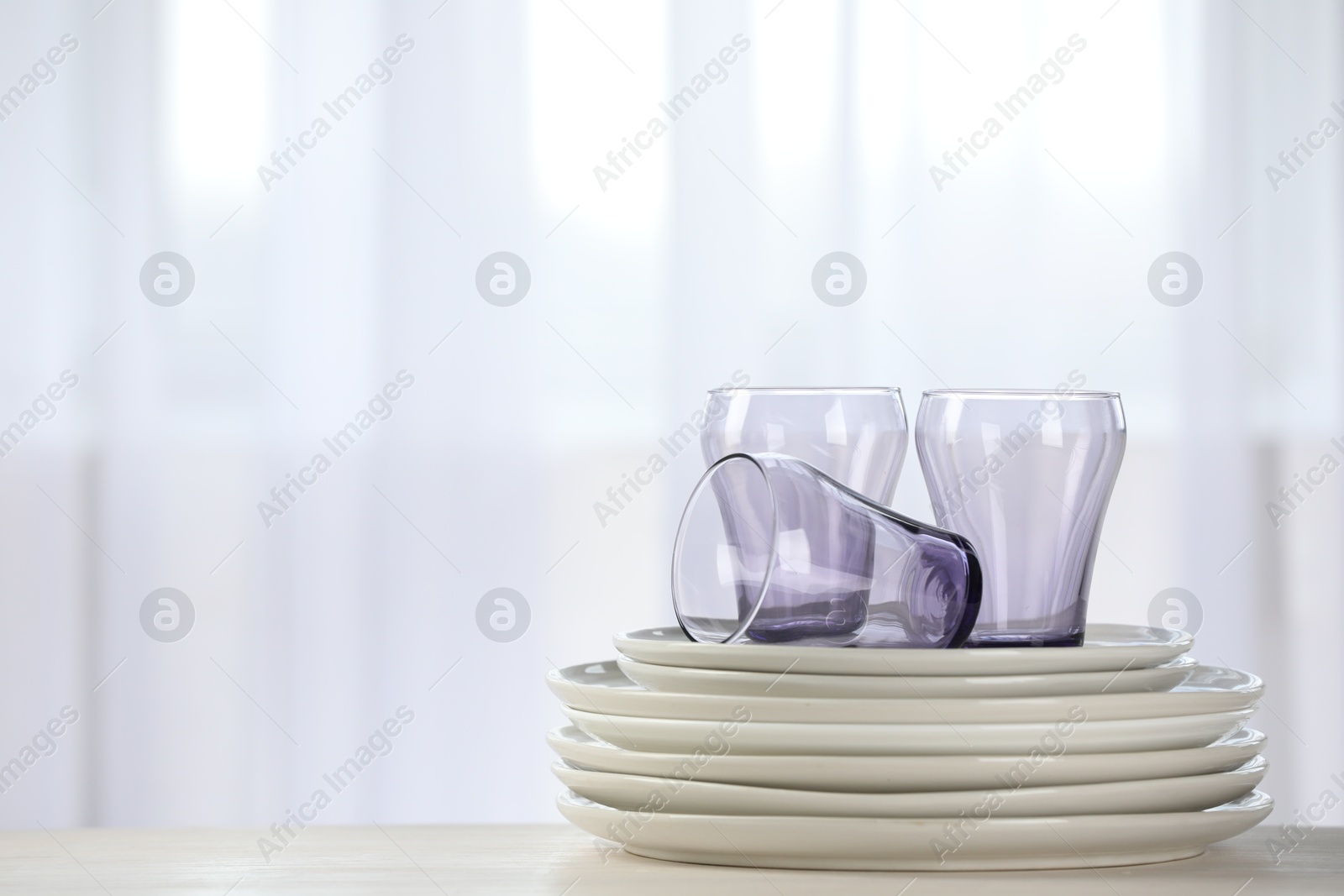 Photo of Empty clean glasses and plates on table indoors, space for text