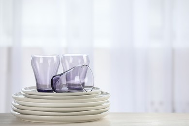 Photo of Empty clean glasses and plates on table indoors, space for text