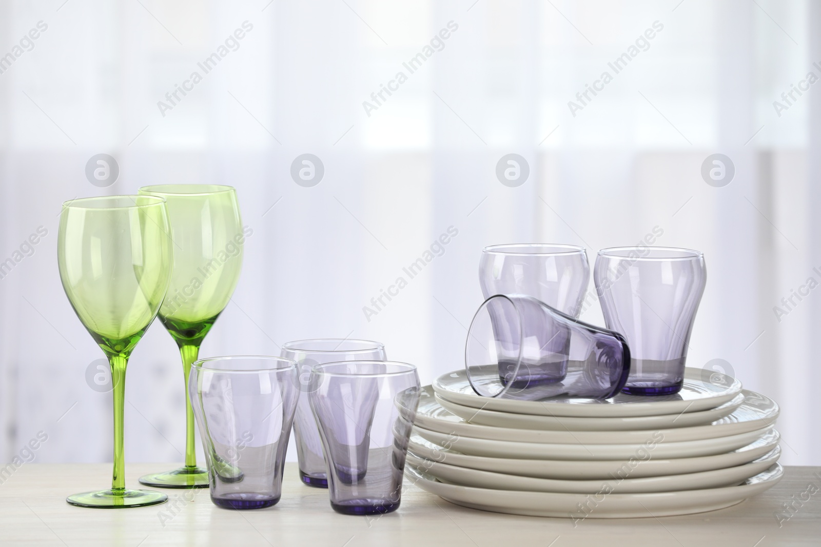 Photo of Empty clean glasses and plates on wooden table indoors