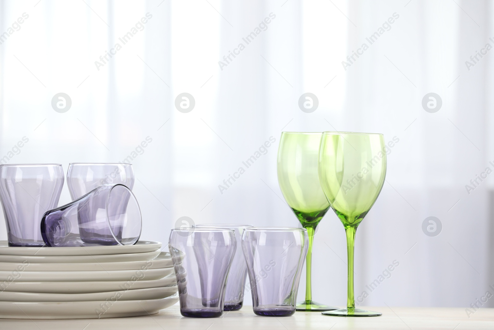 Photo of Empty clean glasses and plates on table indoors