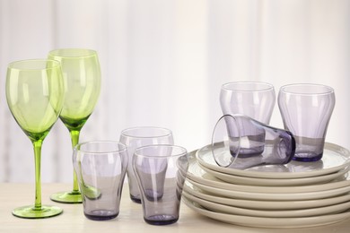 Photo of Empty clean glasses and plates on wooden table indoors