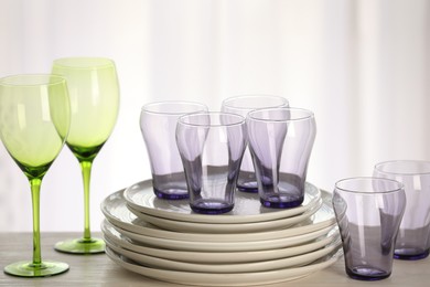 Photo of Empty clean glasses and plates on wooden table indoors