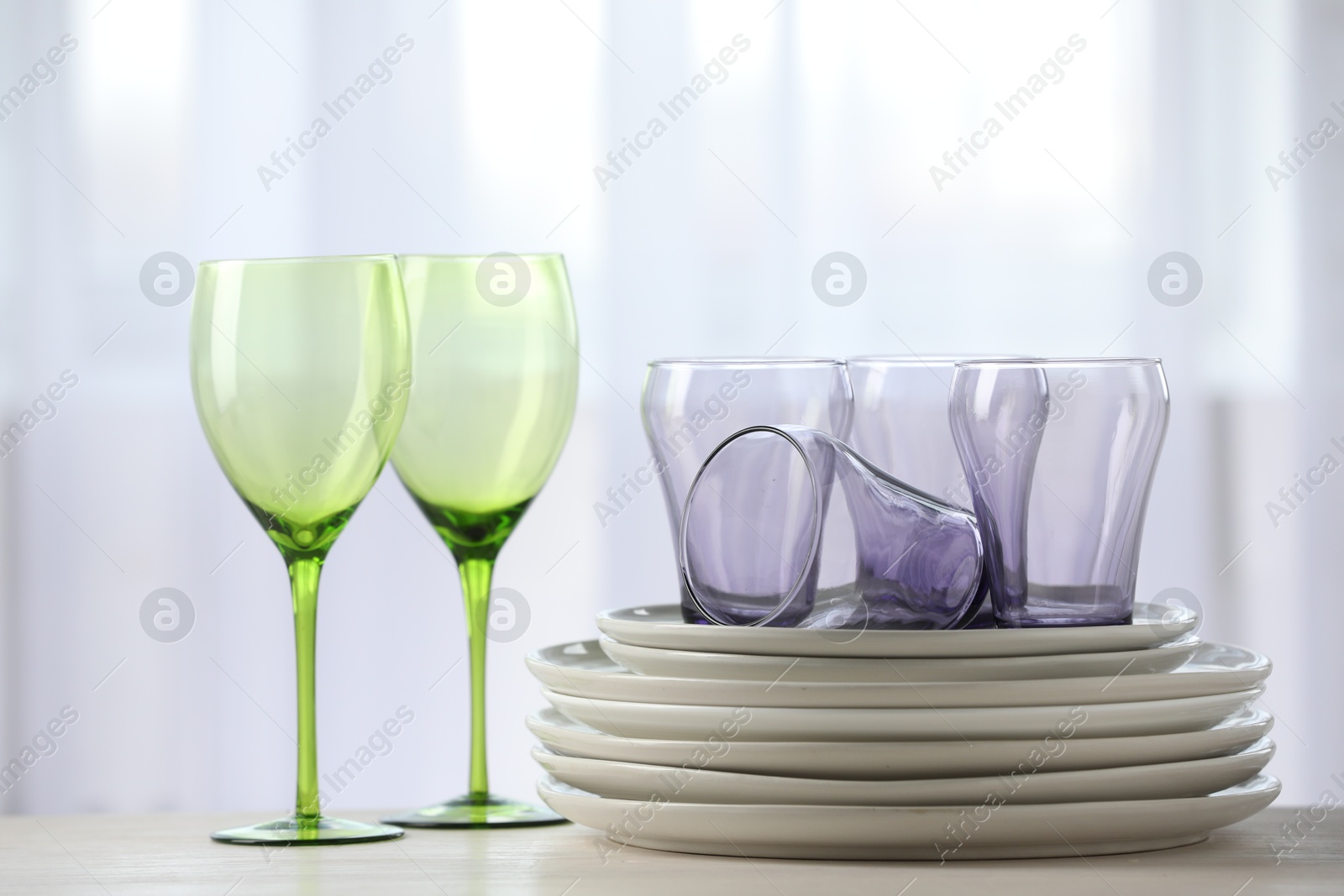 Photo of Empty clean glasses and plates on table indoors