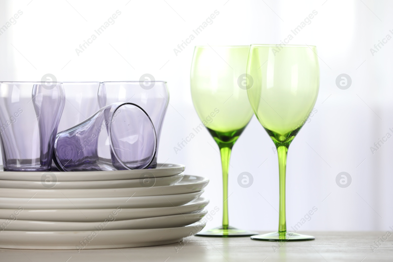 Photo of Empty clean glasses and plates on wooden table indoors