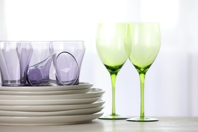 Photo of Empty clean glasses and plates on wooden table indoors