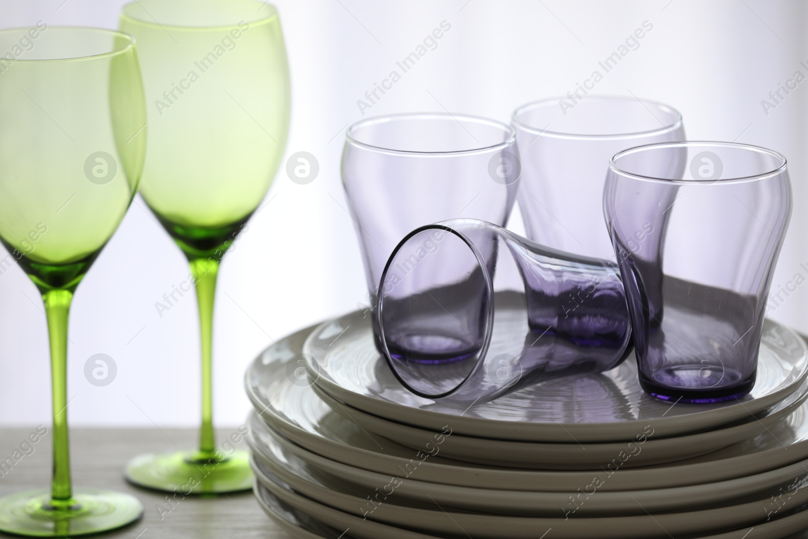 Photo of Empty clean glasses and plates on table indoors, closeup