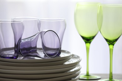 Photo of Empty clean glasses and plates on table indoors, closeup