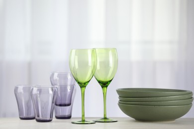 Photo of Empty clean glasses and bowls on table indoors