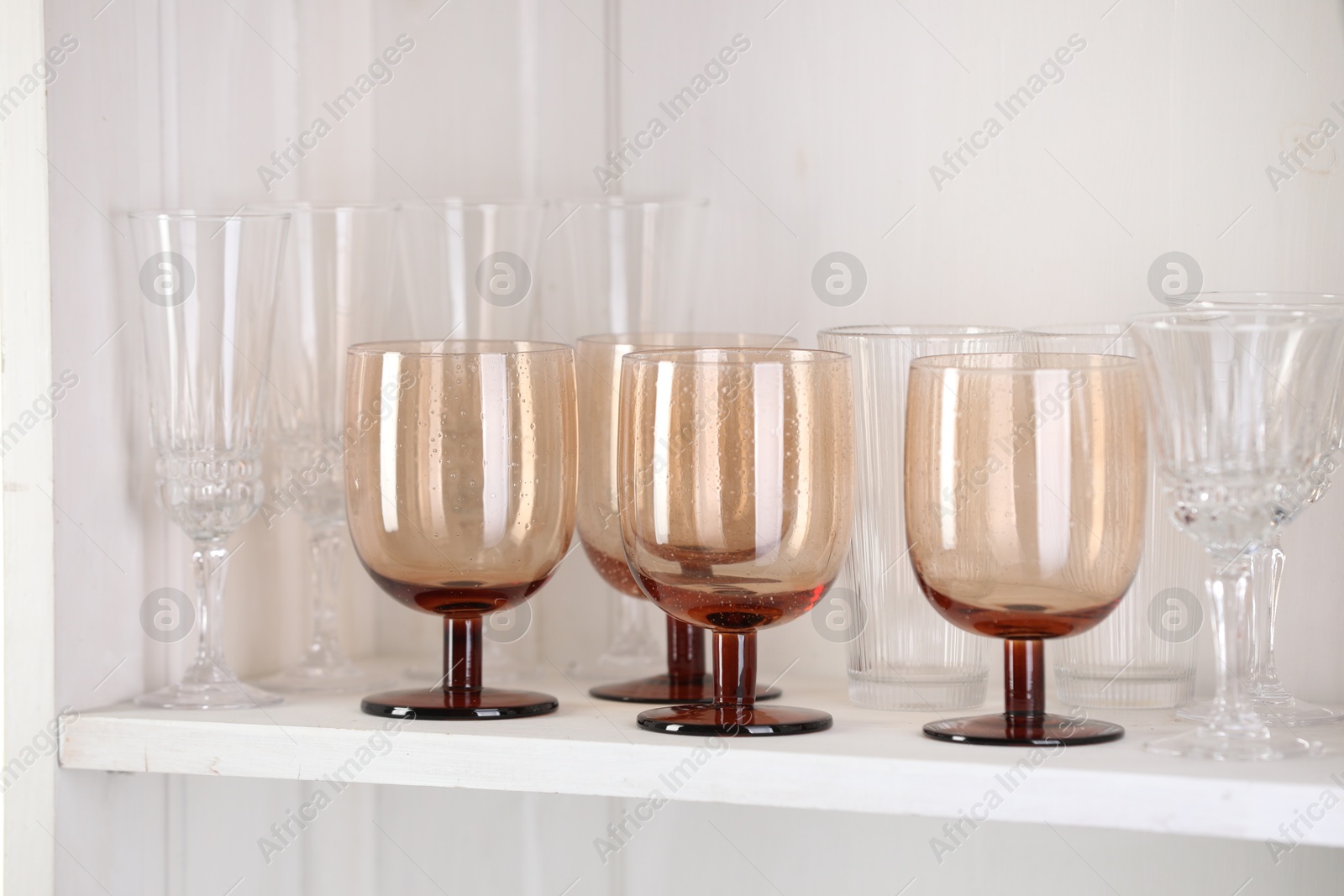 Photo of Different empty clean glasses on white shelf