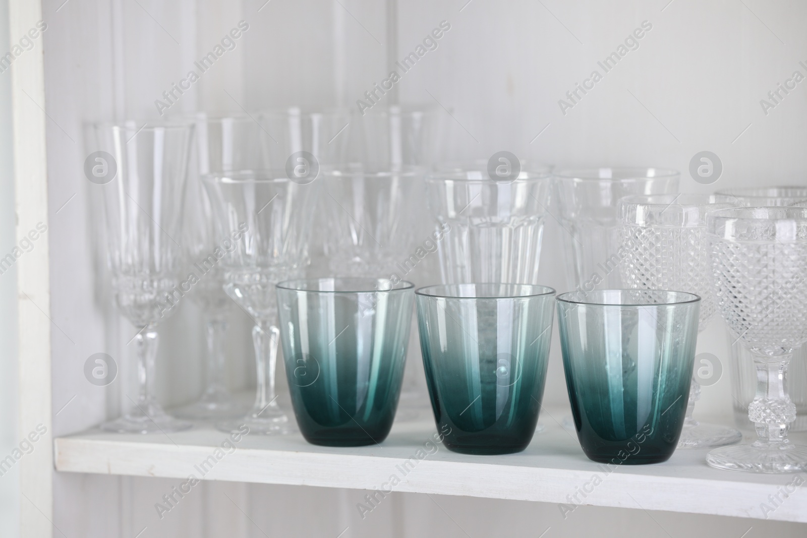 Photo of Different empty clean glasses on white shelf