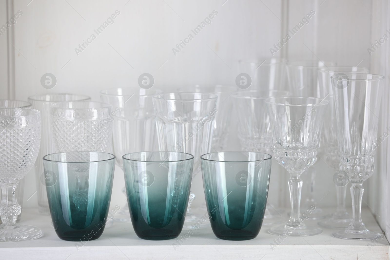 Photo of Different empty clean glasses on white shelf