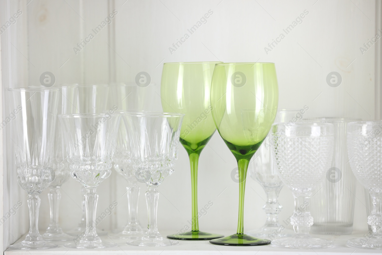 Photo of Different empty clean glasses on white shelf