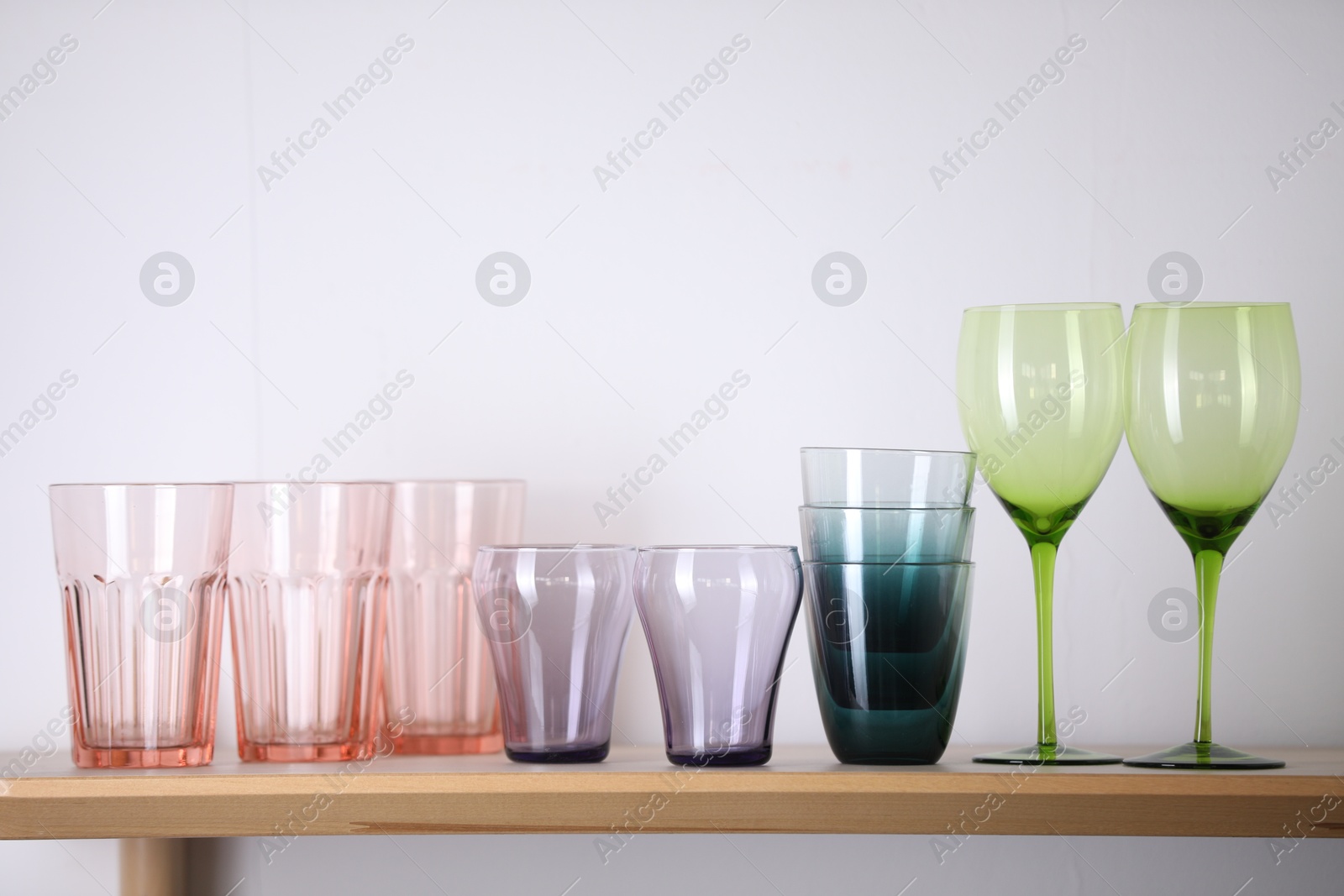 Photo of Empty clean glasses on wooden table near white wall indoors