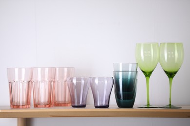 Photo of Empty clean glasses on wooden table near white wall indoors