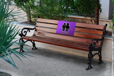 Image of Place where you can receive or give emotional support. Sign with human figures and text Open To Listen on bench outdoors