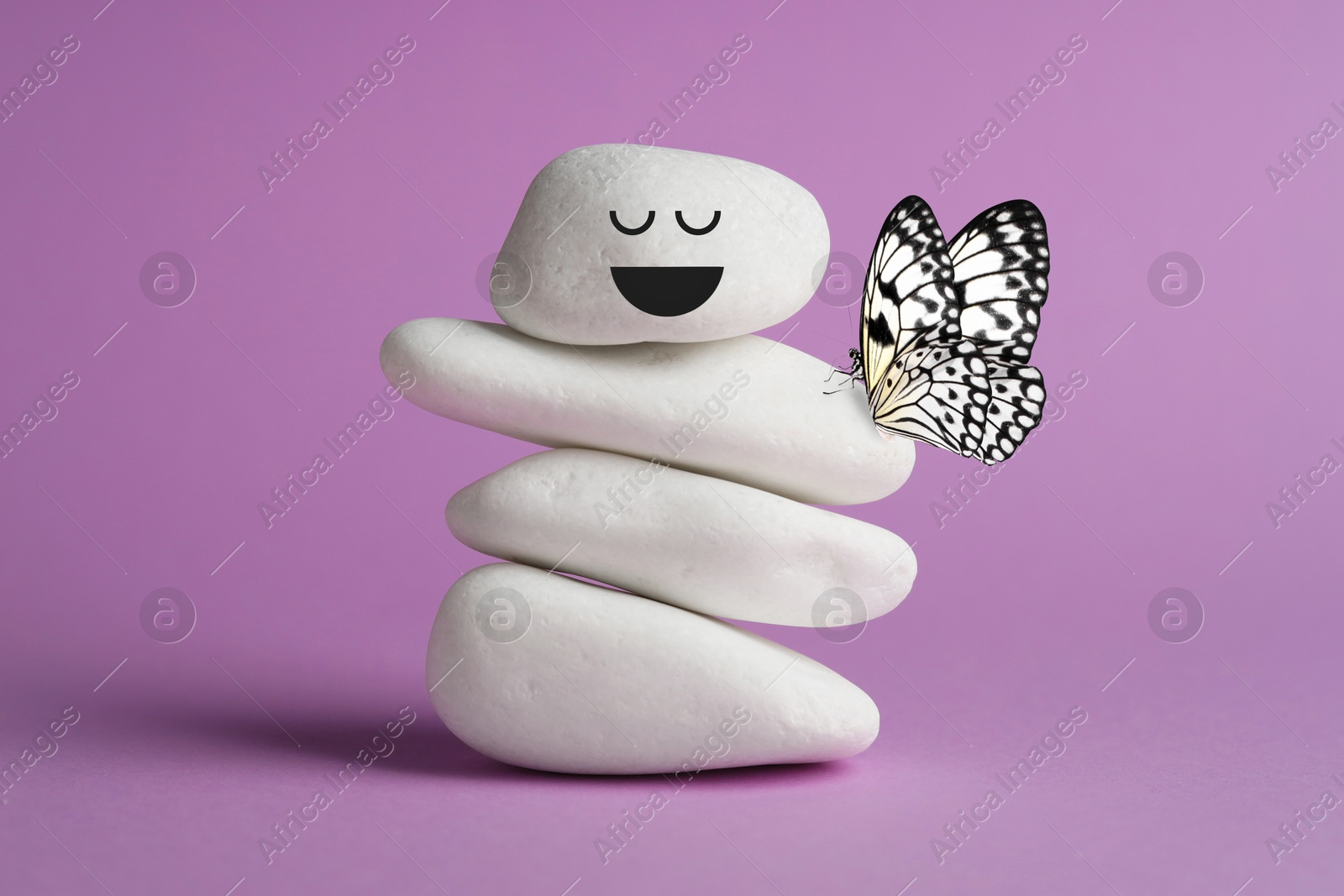 Image of Happy stone glad to see butterfly, harmony. Stacked pebbles and one with smiling face on top against violet background