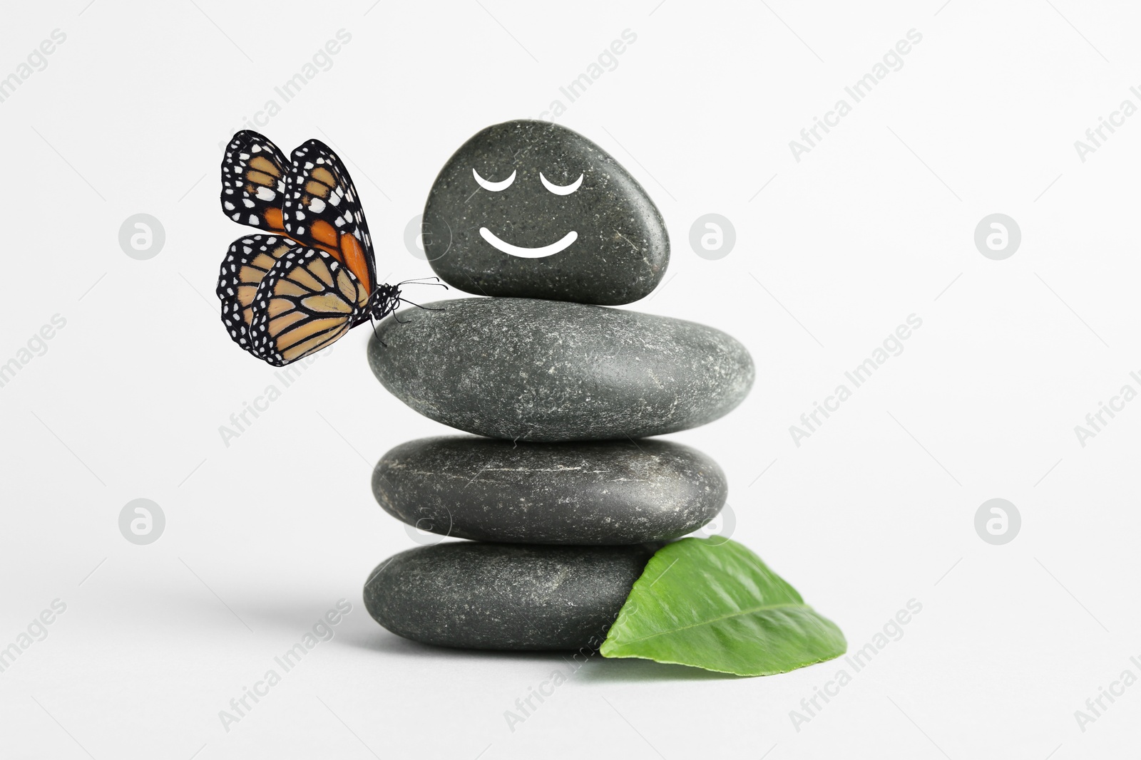 Image of Happy stone glad to see butterfly, harmony. Stacked pebbles and one with smiling face on top against white background