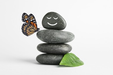 Image of Happy stone glad to see butterfly, harmony. Stacked pebbles and one with smiling face on top against white background