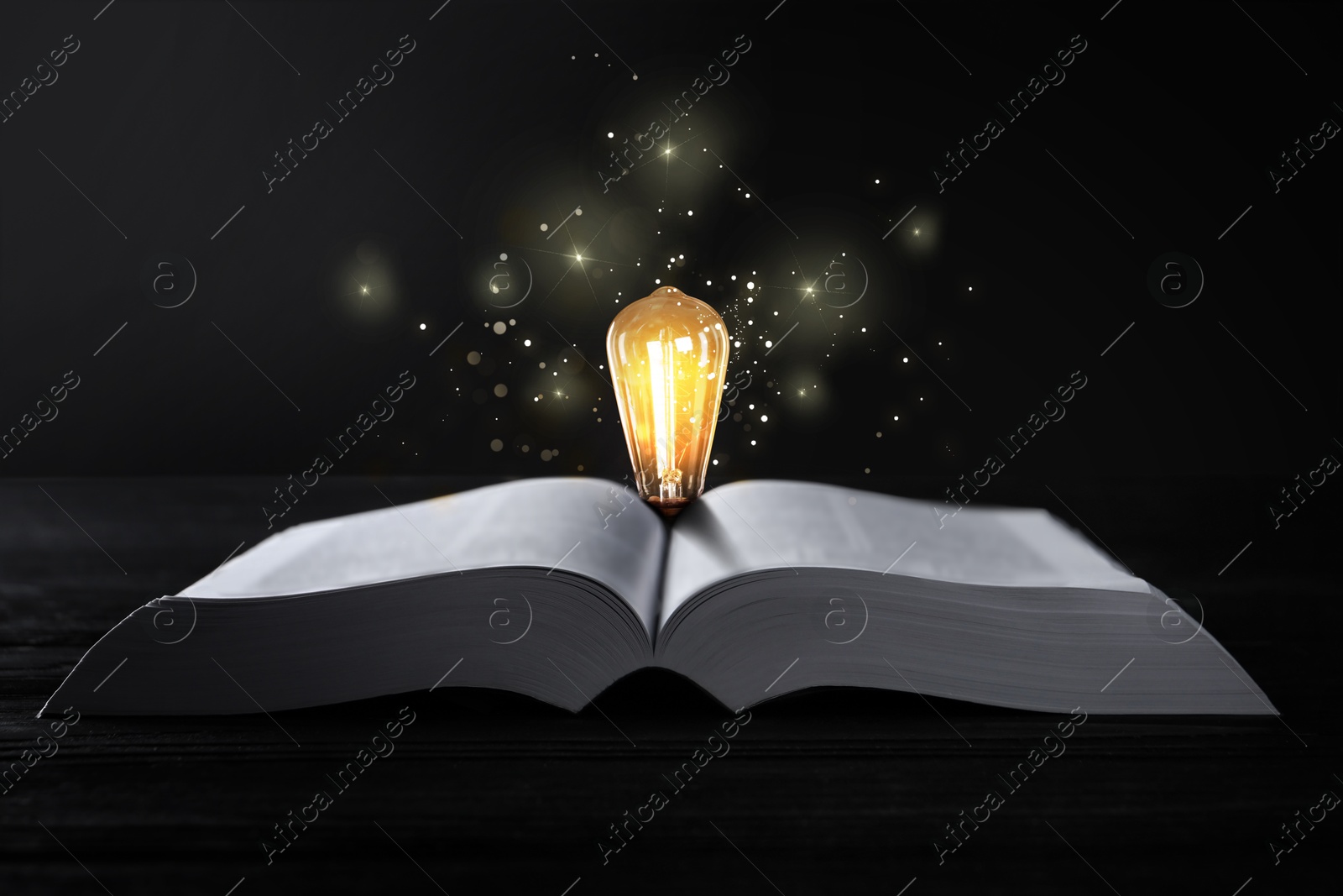 Image of Book and glowing light bulb on wooden table