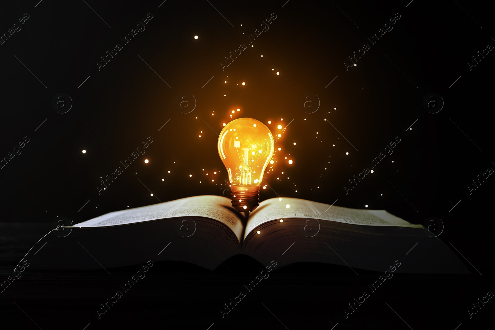 Image of Book with glowing light bulb on table and magic lights