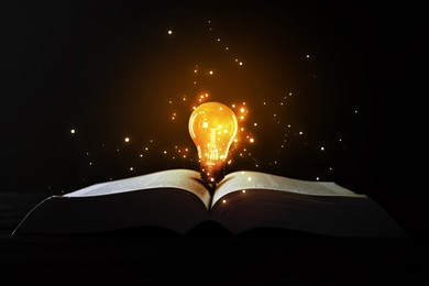 Image of Book with glowing light bulb on table and magic lights