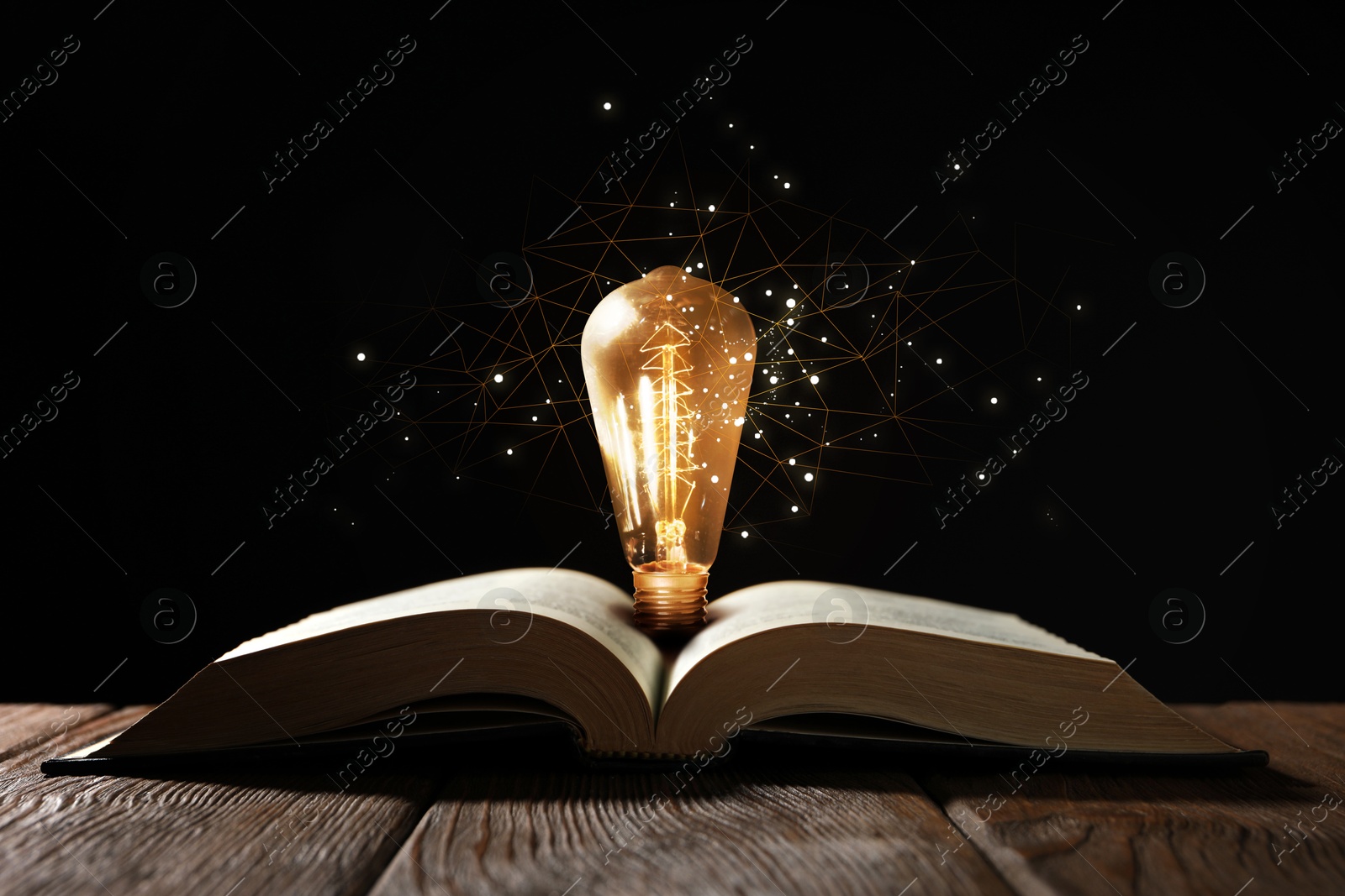 Image of Book with glowing light bulb on wooden table and magic lights